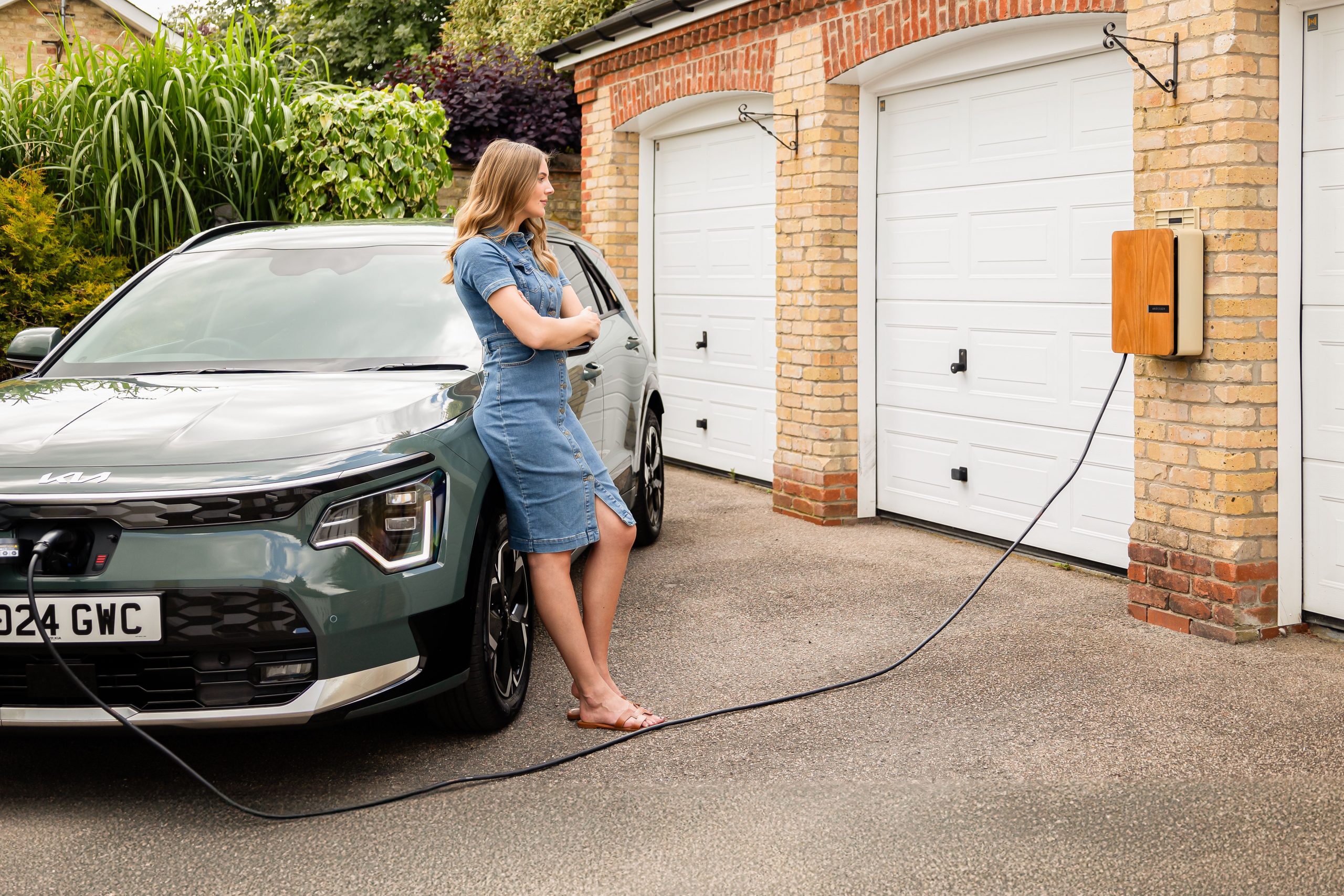 Young lady with an andersen home electric vehicle charge point and all electric kia niro